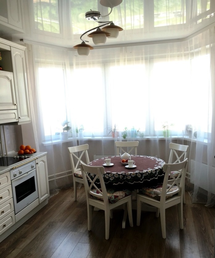 Белый круглый кухонный стол по центру кухни
